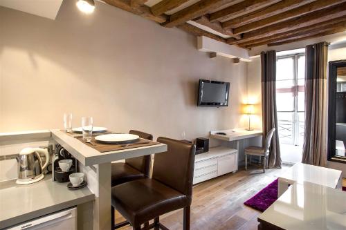 une cuisine et un salon avec une table et des chaises dans l'établissement Habitat Parisien - Marais Sicile, à Paris
