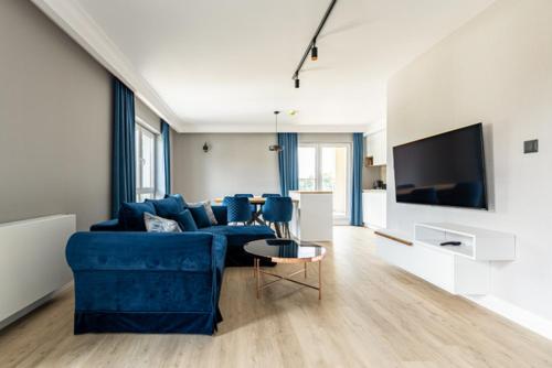 a living room with a blue couch and a tv at Leeloo in Człuchów