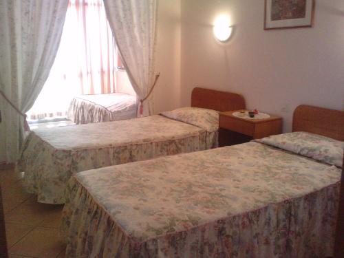 a hotel room with two beds and a window at Residencial Nosso Paraiso in Quarteira