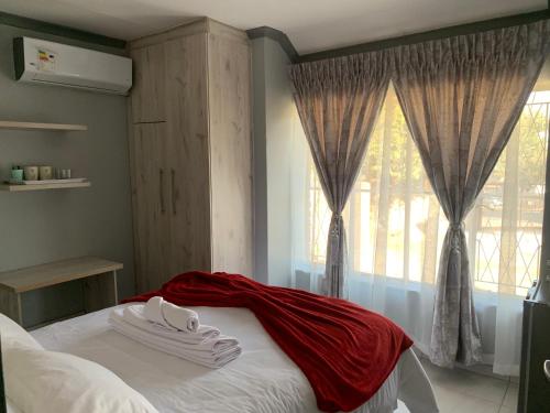 een slaapkamer met een bed met een rode deken erop bij Waterfall View Lodge in Midrand