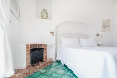 a white bedroom with a fireplace and a bed at Villa Giusy in Positano
