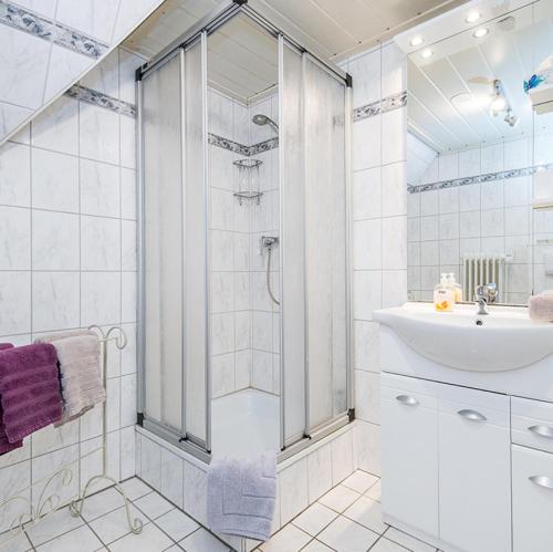 ein weißes Bad mit einer Dusche und einem Waschbecken in der Unterkunft Wohnung Ost in Westerland