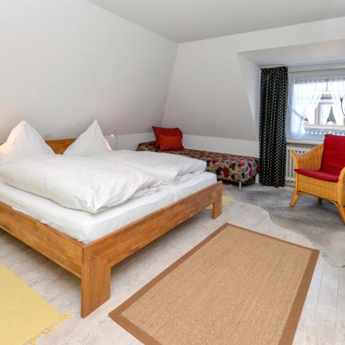 a bedroom with a bed and a red chair at Wohnung West in Westerland
