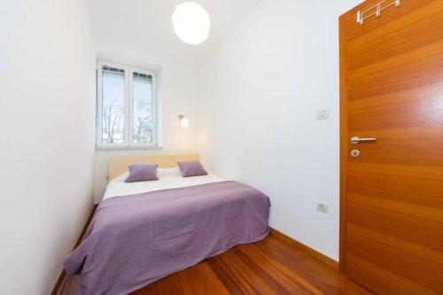 een slaapkamer met een bed met paarse lakens en een houten deur bij Sea Organ Apartment Zadar in Zadar