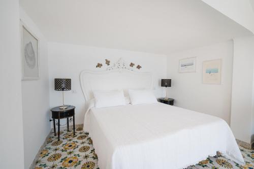 a white bedroom with a white bed and two lamps at Villa Giusy in Positano