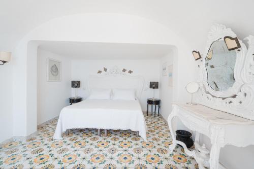 a white bedroom with a white bed and a mirror at Villa Giusy in Positano