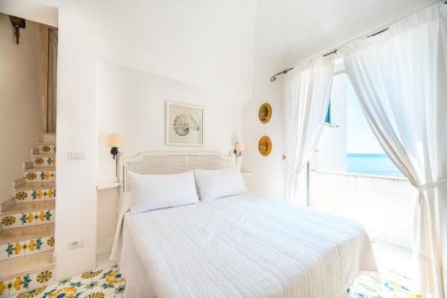 a white bedroom with a bed and a window at Villa Giusy in Positano