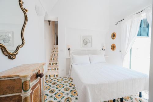 a white bedroom with a bed and a mirror at Villa Giusy in Positano