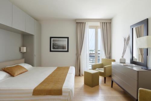 1 dormitorio con 1 cama, TV y silla en Marina di Scarlino Resort, en Puntone di Scarlino