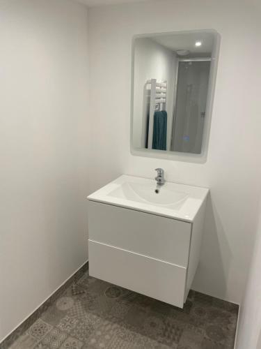 La salle de bains blanche est pourvue d'un lavabo et d'un miroir. dans l'établissement duplex cosy au cœur de Royat, à Royat