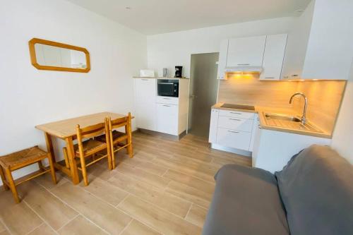 une cuisine avec des armoires blanches, une table et un évier dans l'établissement Appartement 2 pièces plage de Nauzan, à Saint-Palais-sur-Mer