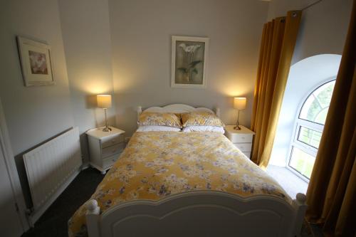 ein Schlafzimmer mit einem Bett mit zwei Nachttischen und einem Fenster in der Unterkunft Mullarts Church -The Glenann Apartment in Knocknacarry