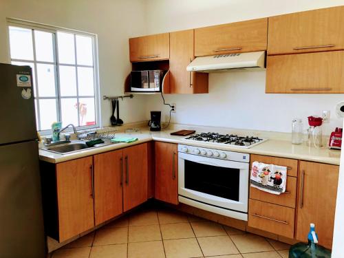 uma cozinha com armários de madeira e um forno de fogão branco em Casa Hestía em Nuevo Vallarta 
