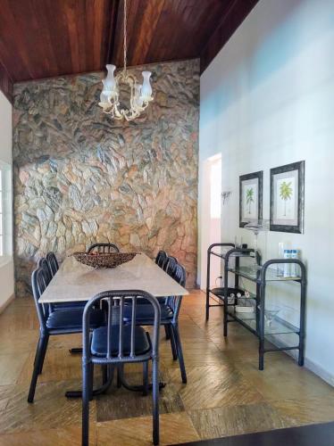 a dining room with a stone wall and a table and chairs at Casa em Escarpas do Lago Ótimo Preço, Aconchegante, Área bem Ampla e Excelente Localização in Capitólio
