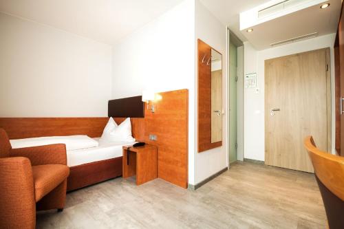 Habitación pequeña con cama y silla. en domus Hotel en Múnich