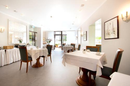 a dining room with white tables and chairs at domus Hotel in Munich
