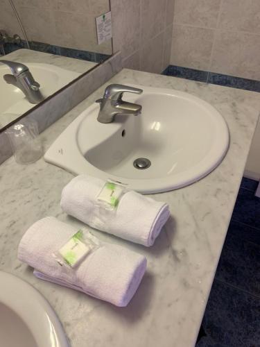 a bathroom sink with two towels on a counter at Hotel Bellevue in Saint-Florent