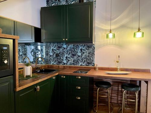 a kitchen with green cabinets and a counter with stools at LA CASITA in Zamora