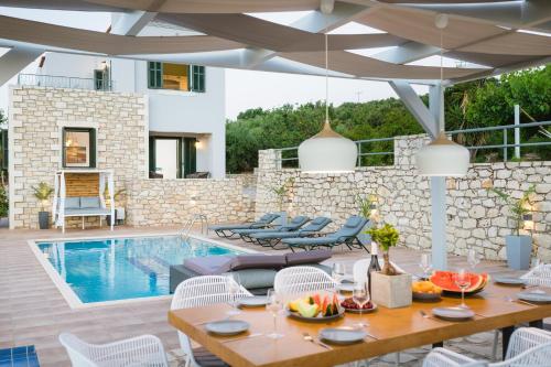 a patio with a table and chairs and a swimming pool at Geo Villas in Skouloúfia