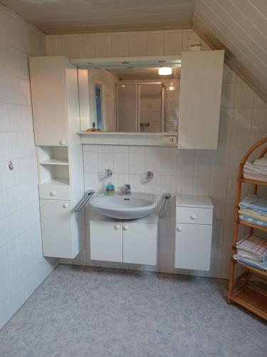 ein Badezimmer mit weißen Schränken und einem Waschbecken in der Unterkunft Ferienhaus Birkenallee in Papenburg