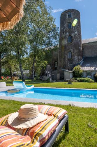 - un chapeau de paille assis sur une chaise près de la piscine dans l'établissement Le Moulin de la Vollerie, à La Tourlandry