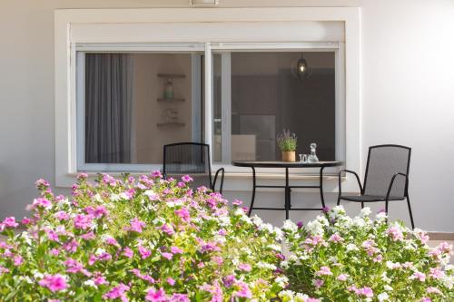 een patio met een tafel en stoelen en roze bloemen bij Kalypso Apartment Ierapetra in Ierápetra