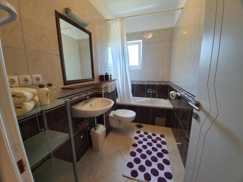 a bathroom with a sink and a toilet and a mirror at Bougenville in Kampor