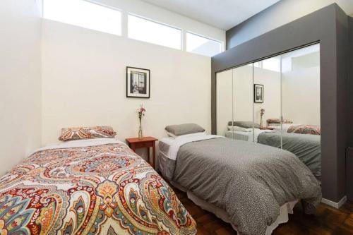 - une chambre avec 2 lits et un grand miroir dans l'établissement 4 Bedroom NYC Apartment, à New York