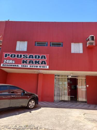 czerwony budynek z samochodem zaparkowanym przed nim w obiekcie Pousada Kaka w mieście Teresina
