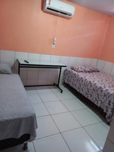 um quarto com duas camas e uma secretária em Pousada Kaka em Teresina