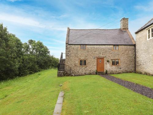 an old stone house on a hill with a grass yard at Ty Tabitha Wynne in Caerwys