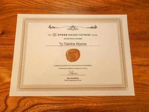 a white card with a medal on a wooden table at Ty Tabitha Wynne in Caerwys