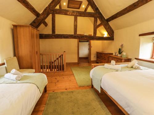 two beds in a room with wooden floors at Ty Tabitha Wynne in Caerwys