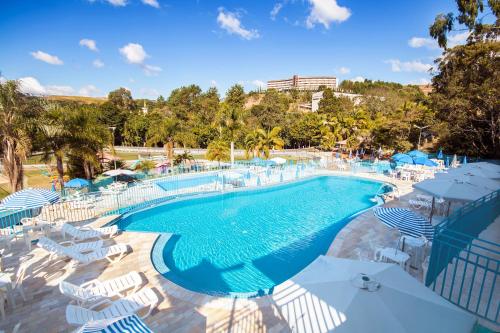 a large swimming pool with chairs and umbrellas at Hotel Vilage Inn All Inclusive Poços de Caldas By Nacional Inn in Poços de Caldas