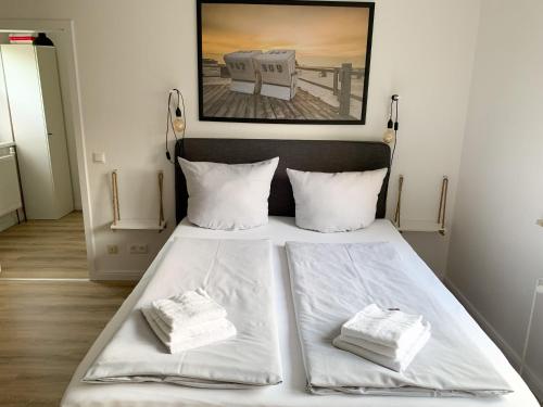 een slaapkamer met een bed met witte lakens en kussens bij Ferienwohnung-Heinke-Urlaub-in-Tating-nahe-St-Peter-Ording in Tating