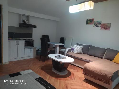 ein Wohnzimmer mit einem Sofa und einem Tisch in der Unterkunft Apartmani Marić In in Vrnjačka Banja