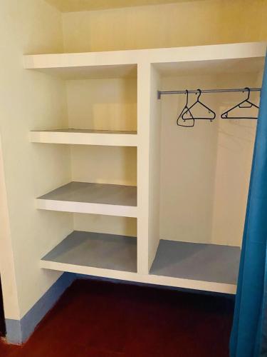 a closet with white shelves and a blue curtain at Hostal La Tortuga Booluda in León