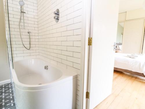 a white bathroom with a tub and a shower at Under Catswood in Stroud