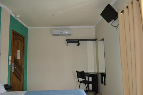 Dormitorio con cama, escritorio y TV en Hotel Poloni, en Itapetininga