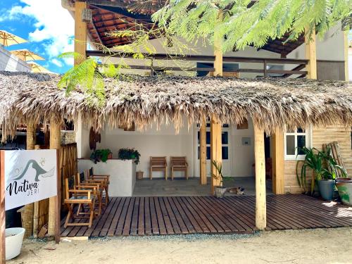 a restaurant with a straw roof and a table and chairs at Pousada Nativa Jeri in Jericoacoara