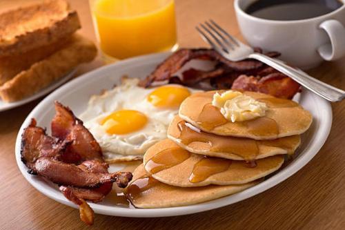 a plate of pancakes with eggs and bacon and a cup of coffee at Crowne Plaza Hotel Orlando Downtown, an IHG Hotel in Orlando
