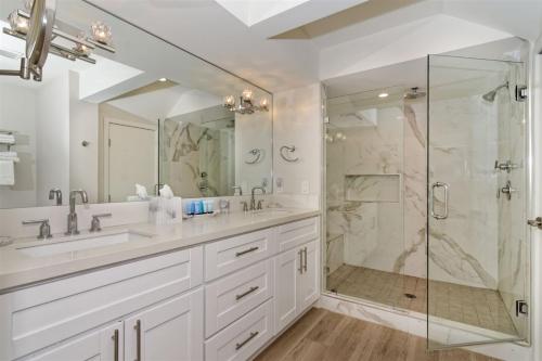 a white bathroom with two sinks and a shower at Ocean Villas Beach Front in Carlsbad