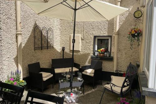 a patio with a table and chairs and an umbrella at Glenmount Castleblayney in Castleblayney