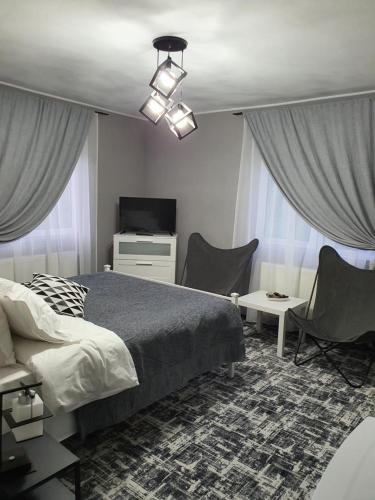 a bedroom with a bed and two chairs and a television at Vila 4 Anotimpuri in Moieciu de Sus