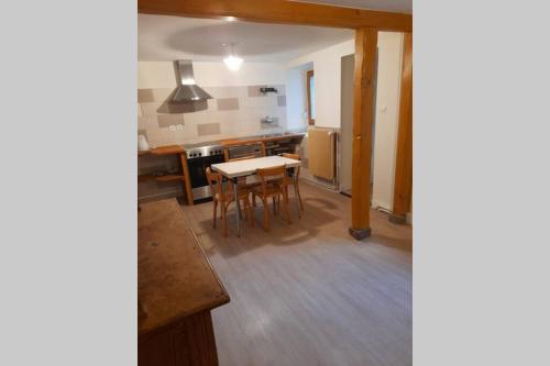 une cuisine avec une table et des chaises dans une pièce dans l'établissement Charmant petit appartement avec bel exterieur., à Saint-Amarin
