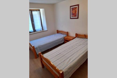 two beds in a room with a window at Charmant petit appartement avec bel exterieur. in Saint-Amarin