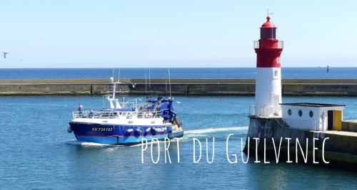 a boat in the water next to a lighthouse at Bord de Mer l'Appartement à Loctudy in Loctudy