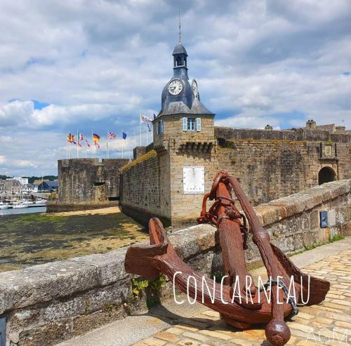 a stone building with a clock tower with flags at Bord de Mer l'Appartement à Loctudy in Loctudy