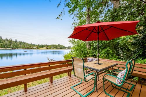 a picnic table with a red umbrella and chairs on a deck at Sound Retreat in Shelton