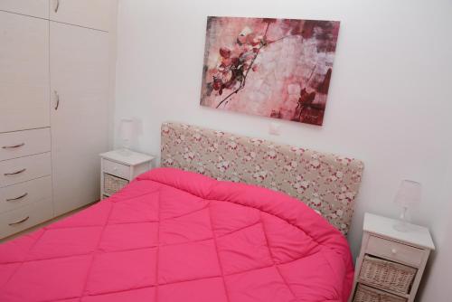 a bedroom with a pink bed and a painting on the wall at Dio Guesthouses in Leonidion
